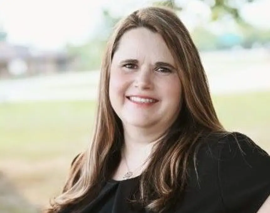 A woman with long hair is smiling for the camera.